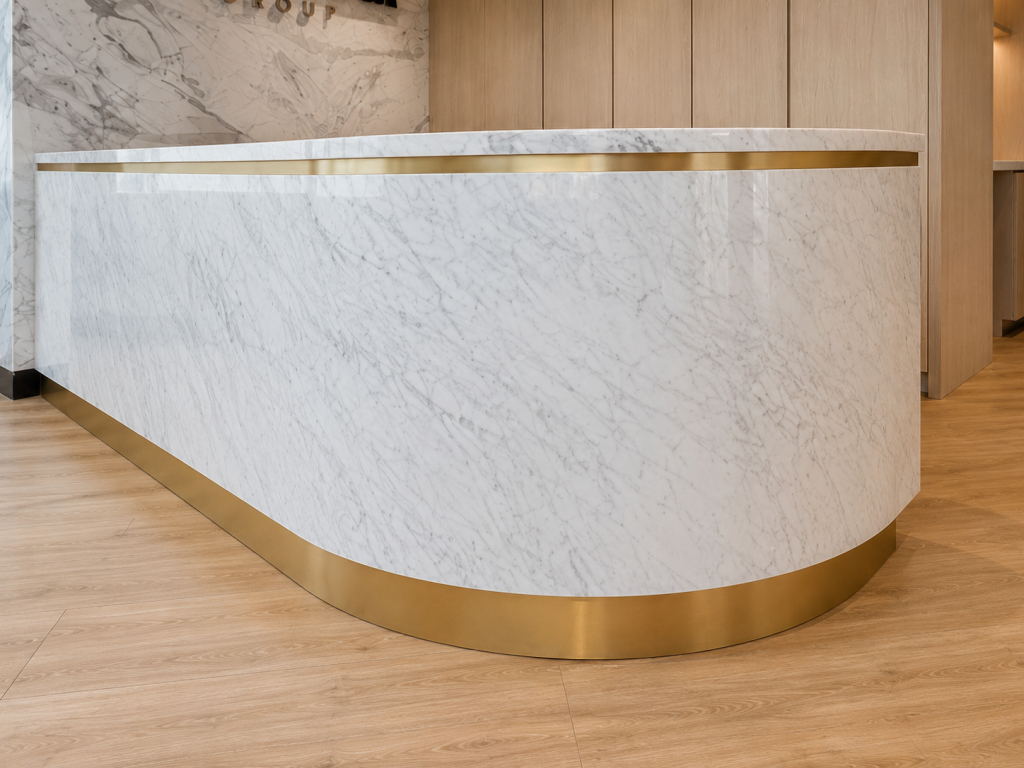 Custom curved marble reception desk with integrated brass reveals, architectural millwork, luxury commercial reception design, and premium workplace interior craftsmanship by Boreal Architectural.