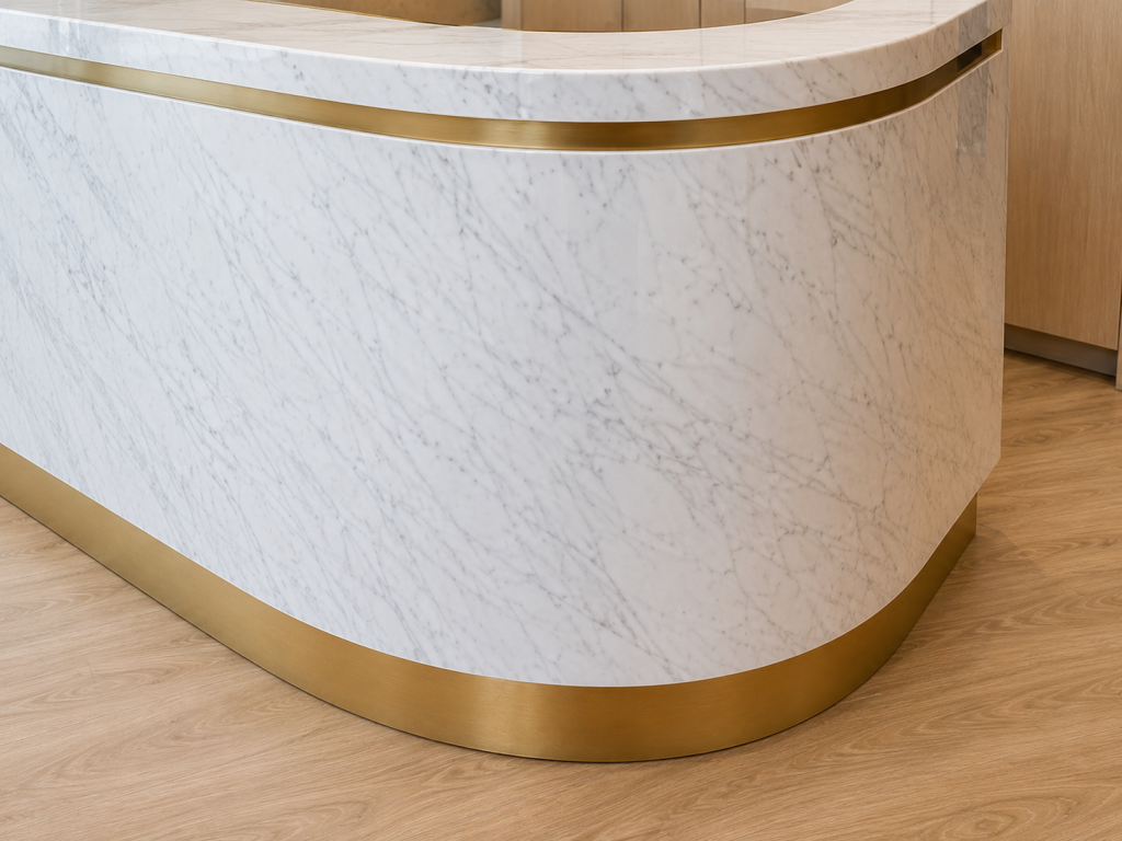 Premium custom marble reception desk featuring curved architectural millwork, integrated brass detailing, luxury commercial office reception, and bespoke interior finishes by Boreal Architectural.