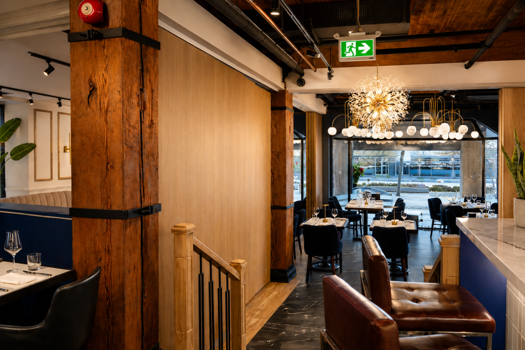 Custom architectural wood wall panels and premium hospitality millwork at BLU Ristorante featuring full-height oak veneer panels, decorative timber columns, bespoke restaurant interiors, architectural wood finishes, and luxury commercial millwork by Boreal Architectural.