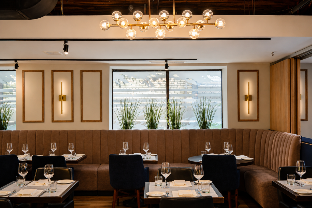 Luxury restaurant interior featuring custom curved banquette seating, architectural wood wall panels, decorative wall mouldings, bespoke hospitality millwork, premium restaurant interiors, and custom commercial wood finishes by Boreal Architectural.