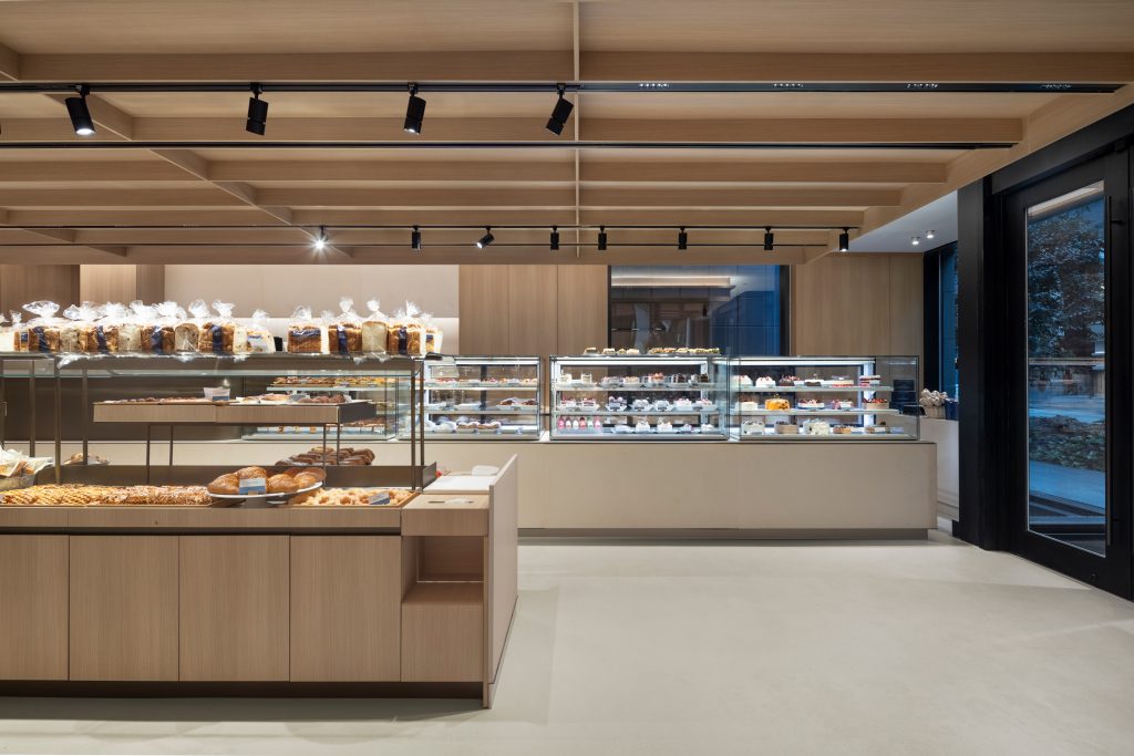 Architectural interior showcasing custom commercial millwork, wood feature ceiling, retail counters, and integrated wall panel systems.