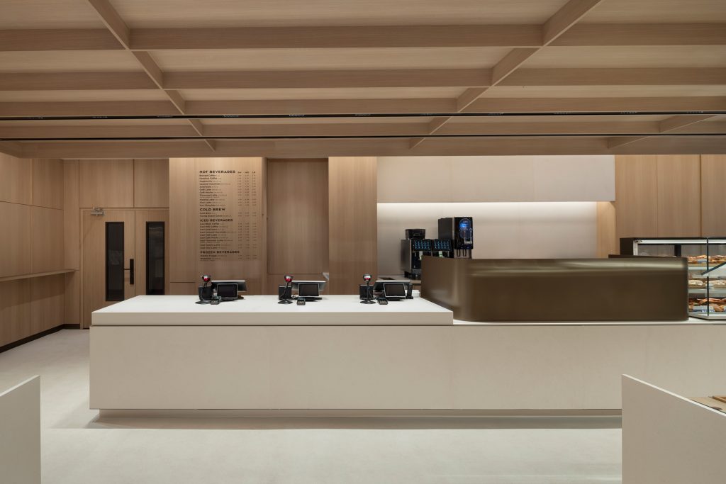 Premium architectural wood wall panels, custom millwork, and integrated commercial wood finishes in a contemporary bakery café.