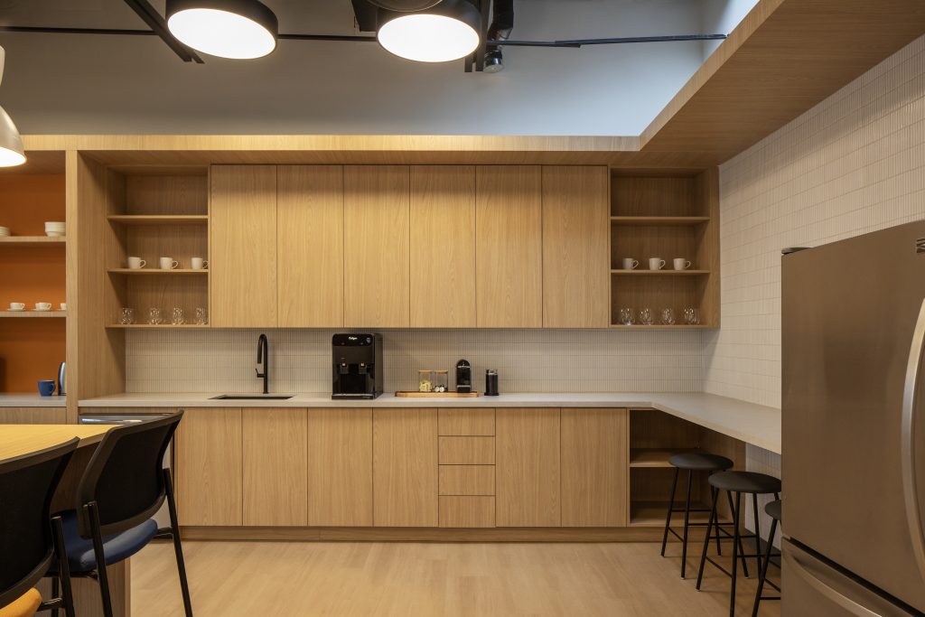 Custom commercial office kitchenette with architectural wood cabinetry, integrated appliance millwork, premium countertops, open shelving, and bespoke workplace millwork manufactured by Boreal Architectural.