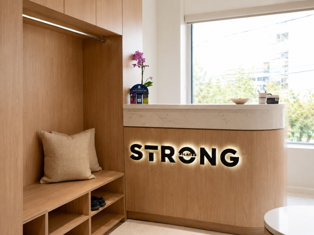 Custom architectural reception desk by Boreal Architectural featuring premium commercial millwork, integrated lighting, precision wood craftsmanship, and contemporary interior finishes for a boutique fitness studio.